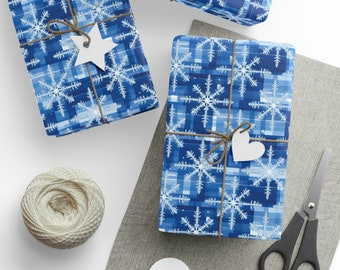 May include: Three wrapped gifts with blue snowflake patterned paper, tied with twine and white tags. A spool of twine, scissors, and additional tags are also visible, suggesting a holiday or winter theme.