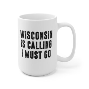 Può includere: Tazza da caffè in ceramica bianca con testo nero che recita "Wisconsin is calling I must go".