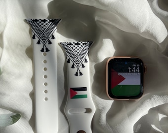 May include: Two white Apple Watch bands with a black and white geometric pattern and a Palestinian flag design. The band on the right is on a gold Apple Watch with a Palestinian flag watch face that reads "FRI 15 1:44 UNLOCK TO VIEW".