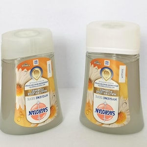 Puede incluir: Se muestran dos botellas de jab&oacute;n Sagrotan Hygiene. Cada botella tiene un cuerpo transparente y gris con una tapa blanca. La etiqueta presenta un dise&ntilde;o de margarita y el texto "HYGIENE SEIFE" y "SAGROTAN".