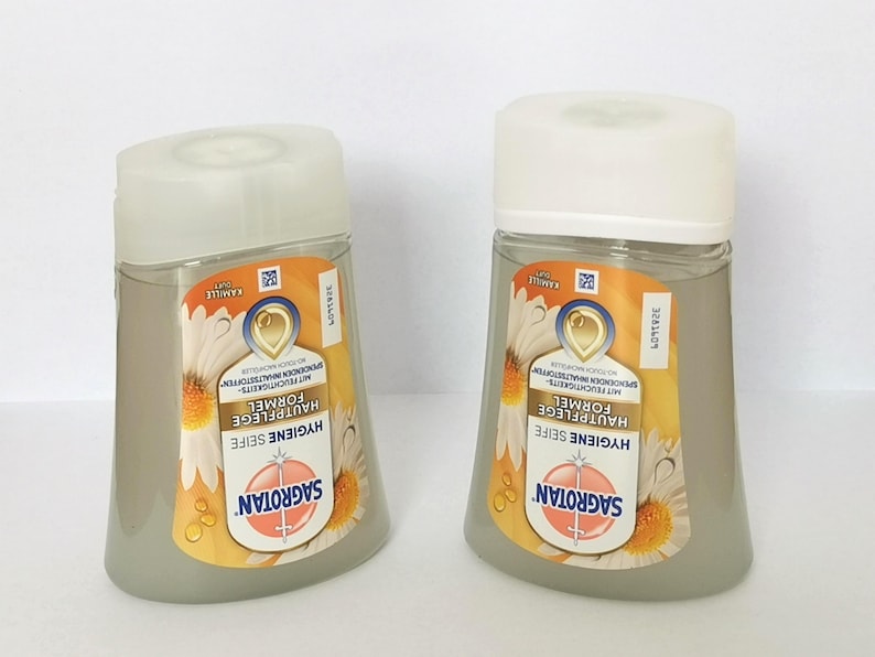 Puede incluir: Se muestran dos botellas de jab&oacute;n Sagrotan Hygiene. Cada botella tiene un cuerpo transparente y gris con una tapa blanca. La etiqueta presenta un dise&ntilde;o de margarita y el texto "HYGIENE SEIFE" y "SAGROTAN".
