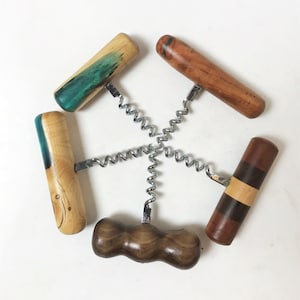 Puede incluir: Un juego de cuatro sacacorchos de madera con diferentes patrones y colores de veta de madera. Los sacacorchos tienen una espiral de metal y un mango de madera.