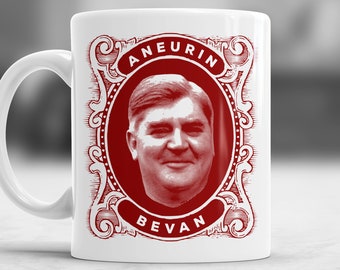 Pode incluir: Caneca de cerâmica branca com uma imagem vermelha de Aneurin Bevan, um político britânico. A imagem é emoldurada com uma borda decorativa e as palavras "Aneurin Bevan" são impressas em vermelho.
