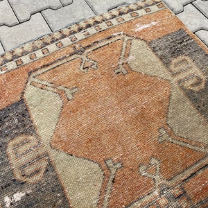 Pu&ograve; includere: Un tappeto vintage con un motivo geometrico in tonalit&agrave; di marrone, beige e nero. Il tappeto ha un aspetto usurato e sbiadito, che gli conferisce un aspetto rustico e antico.