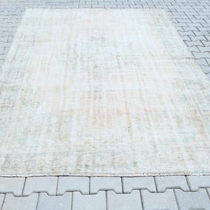 Può includere: Un tappeto rettangolare caratterizzato da un motivo sbiadito e usurato in tonalità tenui di crema, beige e arancione tenue. Il design include un medaglione centrale e un bordo complesso con motivi floreali e geometrici sottilmente logori.