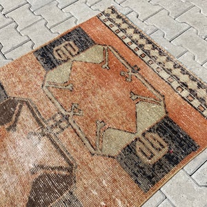 Pu&ograve; includere: Un tappeto vintage con un motivo geometrico in tonalit&agrave; di marrone, beige e nero. Il tappeto ha un aspetto vissuto ed &egrave; fatto di lana.