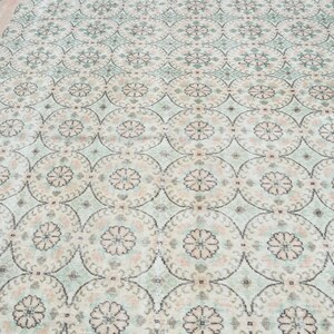 May include: A vintage rug with a cream background and a repeating pattern of light green and pink floral motifs.
