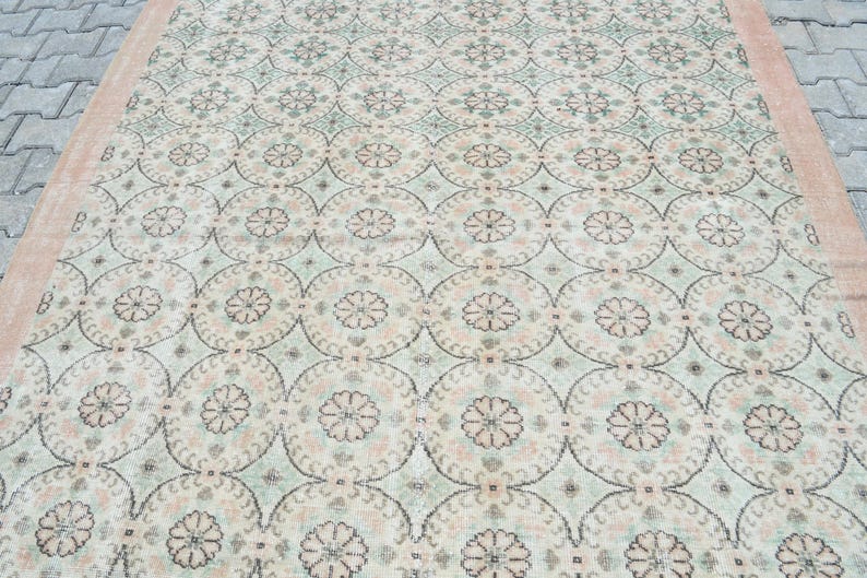 May include: A vintage rug with a cream background and a repeating pattern of light green and pink floral motifs.