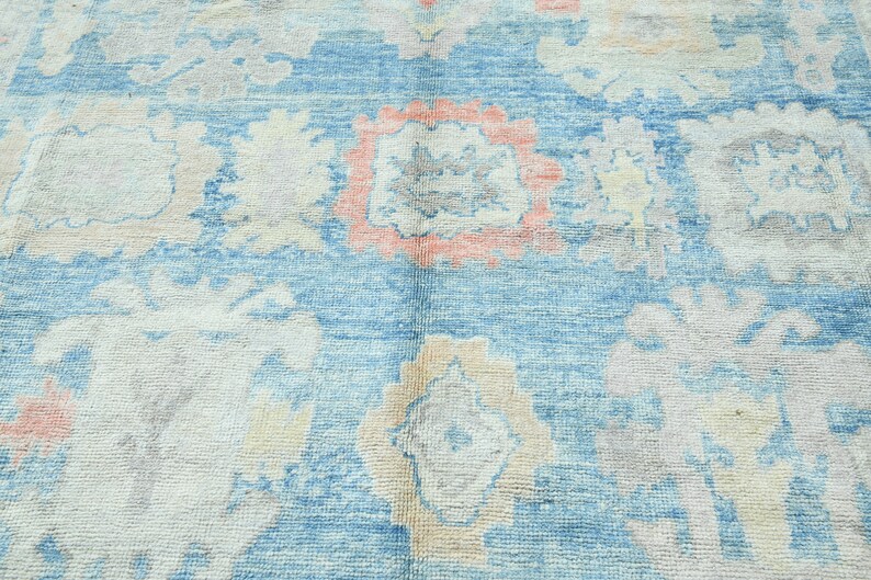 K&ouml;nnte beinhalten: Ein Vintage-Teppich mit blauem Hintergrund und einem floralen Muster in Rosa-, Wei&szlig;- und Graut&ouml;nen.