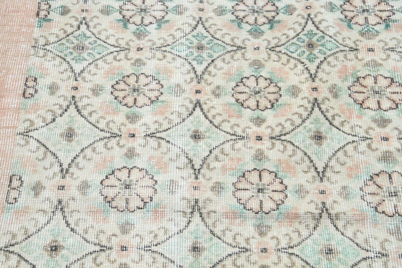 May include: A vintage rug with a repeating pattern of floral motifs in shades of pink, green, and white.