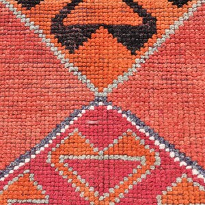 May include: Close-up of a red, orange, and gray patterned rug with a geometric design. The rug is woven with a variety of textures and colors.