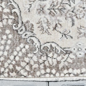 Peut inclure: Un gros plan d'un tapis beige et brun &agrave; motifs avec une bordure frang&eacute;e. Le tapis pr&eacute;sente un motif floral avec un aspect vieilli subtil.