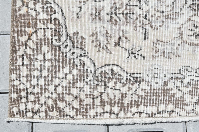Peut inclure: Un gros plan d'un tapis beige et brun &agrave; motifs avec une bordure frang&eacute;e. Le tapis pr&eacute;sente un motif floral avec un aspect vieilli subtil.