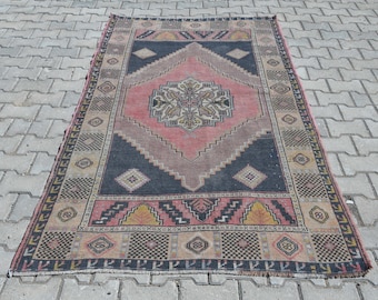 May include: A vintage rug with a traditional Persian design. The rug has a dark blue background with a central medallion in shades of pink, beige, and brown. The border is a cream color with intricate geometric patterns.