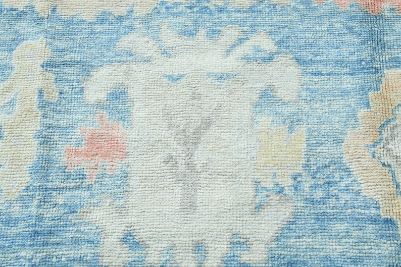K&ouml;nnte beinhalten: Nahaufnahme eines blauen und wei&szlig;en gemusterten Teppichs mit einem verblassten, Vintage-Look. Der Teppich hat eine weiche, strukturierte Oberfl&auml;che und ist aus gewebten Fasern gefertigt.