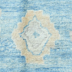 K&ouml;nnte beinhalten: Nahaufnahme eines blauen und wei&szlig;en Teppichs mit dezentem Blumenmuster. Der Teppich hat eine weiche, strukturierte Oberfl&auml;che.