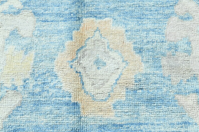 K&ouml;nnte beinhalten: Nahaufnahme eines blauen und wei&szlig;en Teppichs mit dezentem Blumenmuster. Der Teppich hat eine weiche, strukturierte Oberfl&auml;che.