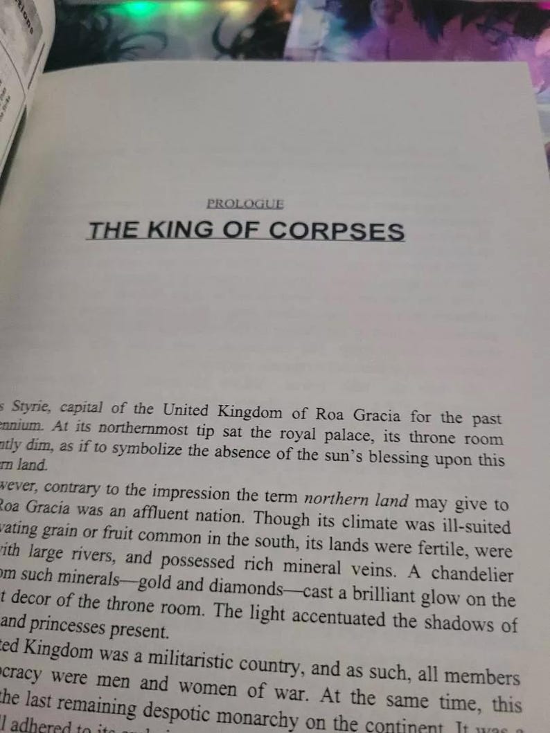 May include: A page from a book titled "The King of Corpses" with text about the capital city of Styrie, the United Kingdom of Roa Gracia, and its northernmost tip where the royal palace is located.