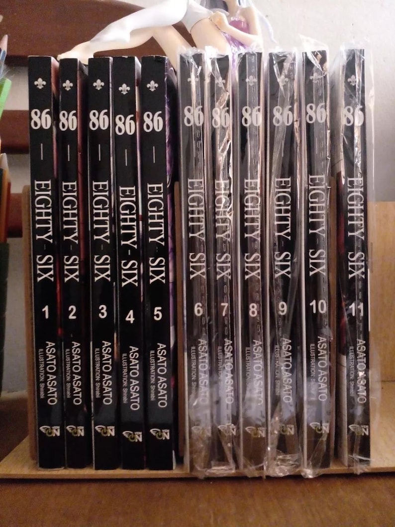May include: A collection of eleven black and white manga volumes with the title "86 - Eighty Six" and volume numbers 1 through 11. The books are arranged in order from left to right.