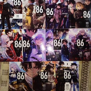 May include: A collection of 11 manga volumes of the series "86 - Eighty Six" by Asato Asato. The covers feature colorful illustrations of characters from the series, including a young woman with blue hair and a young man with brown hair.