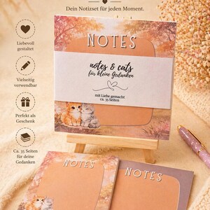 Könnte beinhalten: Ein Set mit Haftnotizen zum Thema Katze, auf denen jeweils das Wort "NOTES" steht. Das Set enthält eine kleine Holzstaffelei und einen Stift. Die Notizen zeigen Kätzchen-Illustrationen und Text auf Deutsch.