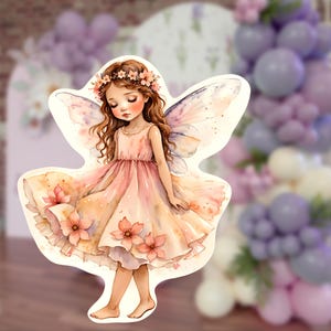 May include: A watercolour illustration of a fairy with long brown hair, a floral crown, and delicate wings. She wears a pink and peach dress decorated with flowers. The fairy is standing, with a blurred background of balloons and floral decorations.