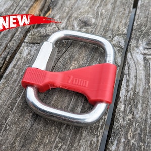 Op de afbeelding: Een zilveren metalen karabijnhaak met een rode plastic hoes. De hoes heeft de tekst "7mm" erop gedrukt.