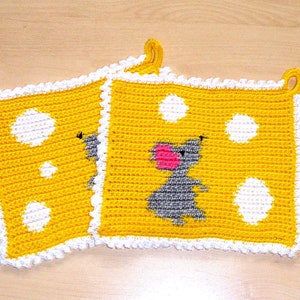 Könnte beinhalten: Zwei gelbe gehäkelte Topflappen mit weißen Punkten und einem weißen gehäkelten Rand. Ein Topflappen zeigt eine graue Maus mit einer rosa Nase.