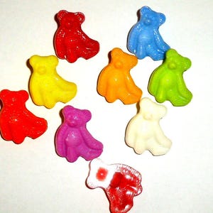 Könnte beinhalten: Eine Ansammlung bunter Gummibärchen in verschiedenen Farben, darunter Rot, Gelb, Blau, Grün, Orange, Lila und Weiß. Die Süßigkeiten sind auf einer weißen Oberfläche angeordnet.
