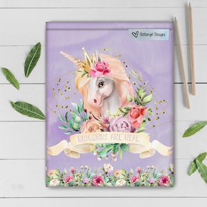 May include: A purple background with a white unicorn with a gold crown and flowers. The unicorn is surrounded by flowers and the text "unicorns are real" is written on a white ribbon.