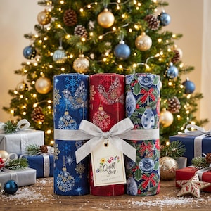 Può includere: Tre rotoli di tessuto legati insieme con un nastro argentato e un'etichetta con la scritta Quilt Shop Ruth Baudisch. I rotoli presentano motivi festivi tra cui fiocchi di neve blu, uccelli rossi e agrifoglio verde con decorazioni natalizie.