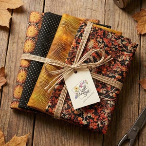 Peut inclure: Une pile de quatre carrés de tissu pliés attachés avec de la ficelle et une étiquette portant l'inscription Quilt Shop Ruth Baudisch. Les tissus présentent des motifs de fleurs orange, de pois blancs sur fond noir, un dégradé jaune et un imprimé floral noir.