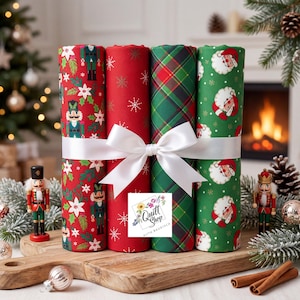 Könnte beinhalten: Vier Stoffrollen, die mit einem weißen Band zusammengebunden sind. Die erste Rolle zeigt Nussknacker und Weihnachtssterne auf Rot, die zweite weiße Schneeflocken auf Rot, die dritte ein grün-rotes Schottenmuster und die vierte Weihnachtsmann-Gesichter auf Grün.