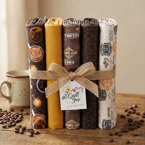 May include: A bundle of rolled fabric, tied with twine and a bow, featuring coffee-themed patterns and solid colors. The fabrics include designs with coffee cups, beans, and text. A tag with the text "Quilt Shop" is attached.