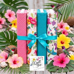 May include: Four folded fabric bolts tied with a turquoise ribbon. The bolts feature pink polka dots, a white floral pattern with hummingbirds, solid turquoise, and a white floral print with hummingbirds. A logo reads Quilt Shop Ruth Baudisch.