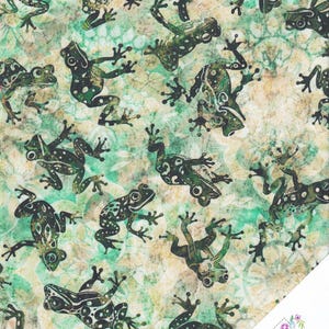 Könnte beinhalten: Stoff mit einem sich wiederholenden Muster aus grünen und schwarzen Fröschen auf einem melierten grün-beigen Hintergrund. Die Frösche haben detaillierte Muster und sind in verschiedenen Posen. Die untere rechte Ecke hat ein Logo mit der Aufschrift "Quilt Shop".