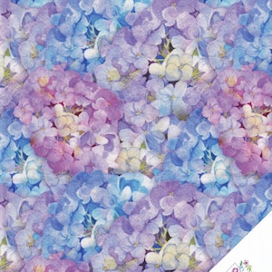May include: A fabric pattern with a watercolour design of hydrangea flowers in shades of blue, purple, and pink. The flowers are densely packed, creating a vibrant floral print. The lower right corner has a logo that says "Quilt Shop" and "Ruth Baudisch".