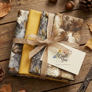 Può includere: Un fascio di quadrati di tessuto legati con spago e un fiocco, con motivi a foglie e corteccia d'albero, e un giallo senape pieno. È allegata una carta con il testo "Quilt Shop". La scena comprende ghiande, pigne e forbici.