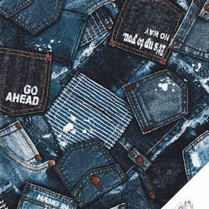 Può includere: Un tessuto blu e bianco con un design a patchwork di tasche in denim. Le tasche hanno varie frasi stampate su di esse, tra cui "Go Ahead", "Hang In" e "It's up to you. No Way".