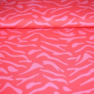 Könnte beinhalten: Roter Stoff mit einem rosa Zebra-Streifenmuster. Der Stoff ist gefaltet, wodurch das Muster im Detail zu sehen ist. Das Design weist geschwungene, unregelmäßige Streifen auf und erzeugt einen auffälligen Textil.