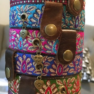 May include: A stack of colorful, patterned cat collars with leather accents and metal charms. The charms feature paw prints and the words "my cat".