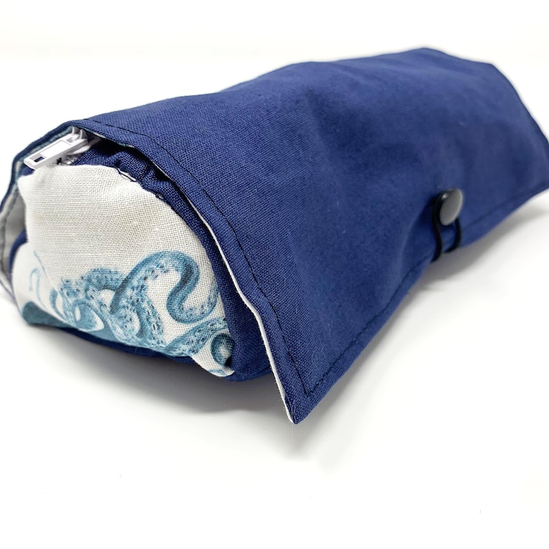 Pode incluir: Uma bolsa azul com z&iacute;per com um forro de tecido branco com estampa de polvo. A bolsa tem um fecho de press&atilde;o.