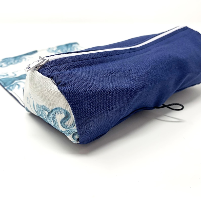 Pode incluir: Um estojo de l&aacute;pis de tecido azul e branco com fecho de correr e cord&atilde;o. O estojo apresenta um padr&atilde;o de polvos azuis e brancos.