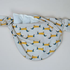 Può includere: Una borsa di tessuto bianco con una stampa di bassotto giallo. La borsa è legata in cima e ha una fodera bianca.