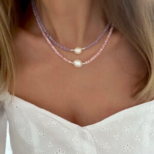May include: Two layered necklaces with pink and purple beads and a pearl pendant.