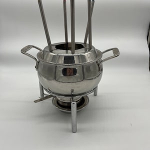 May include: A stainless steel fondue pot with a round base and a stand with three legs. The pot has a lid with a hole for dipping forks. Six dipping forks are included.