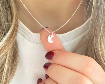 May include: A silver necklace with a crescent moon pendant featuring a small star. The pendant is delicate and minimalist.