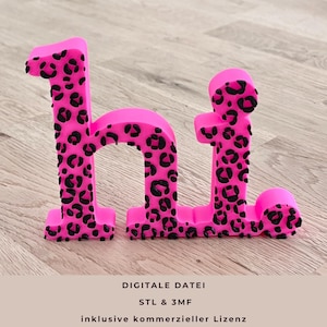 May include: A bright pink, 3D-printed word "hi" with a black leopard print pattern. The letters are standing upright on a wooden surface. The image also contains text at the bottom.