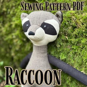 May include: A stuffed raccoon doll with a gray body, black and white facial markings, and black arms. The text "SEWING PATTERN PDF" is at the top, and "RACCOON" is at the bottom. The background is green moss.