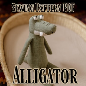 Puede incluir: Un juguete de peluche de un caimán verde con dientes y ojos blancos. Se muestra el texto "SEWING PATTERN PDF" y "ALLIGATOR". El caimán está sentado en una cesta tejida.